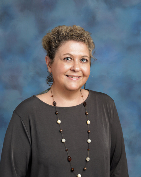 Teacher smiling against a blue background