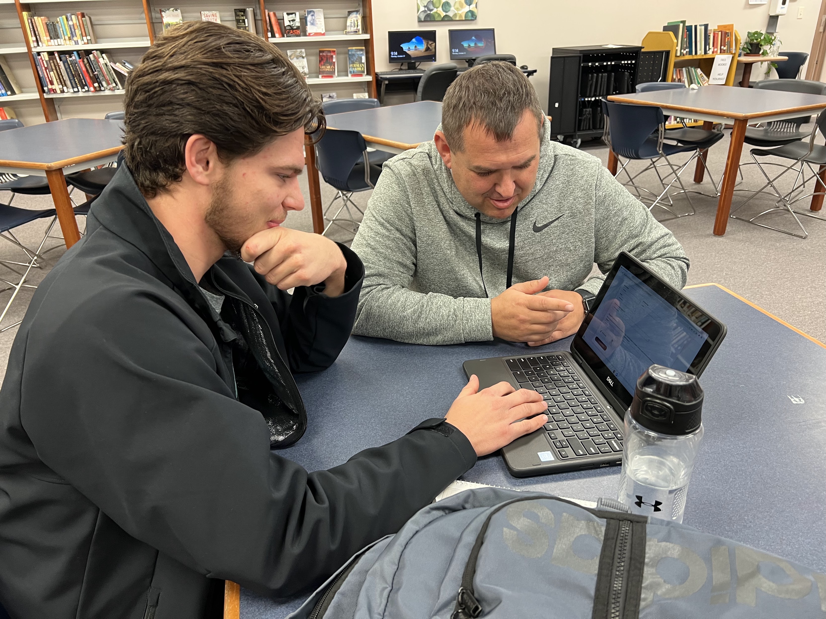 Administrator and student look at laptop