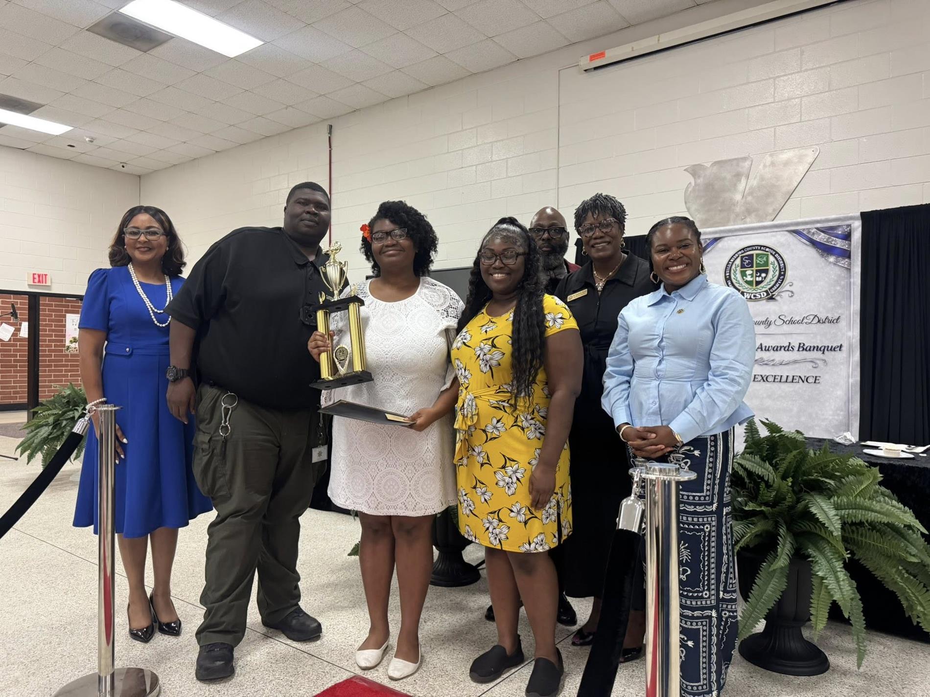 people standing together. one is receiving an award 