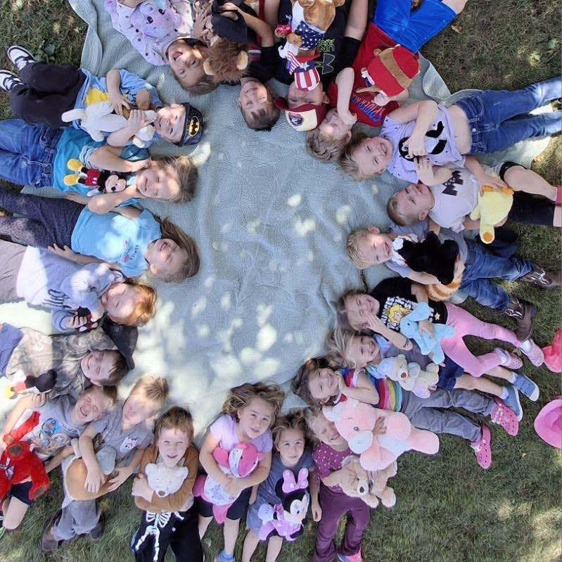 MCS students laying in a circle under a tree with their favorite stuffed animal.