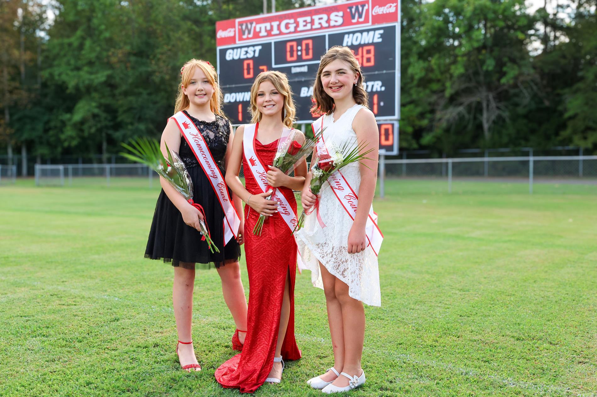 5th grade homecoming girls in red, white and black dresses with red roses