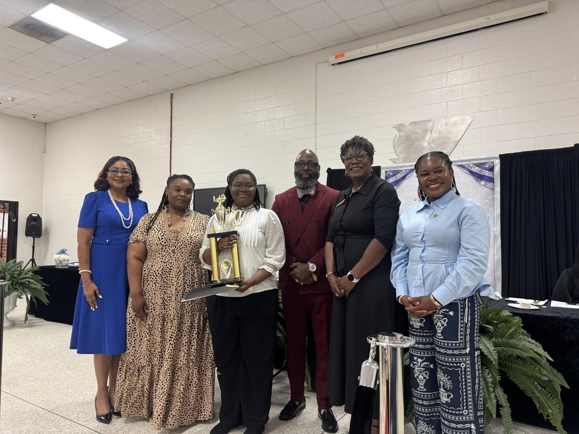 people standing together. one is receiving an award 