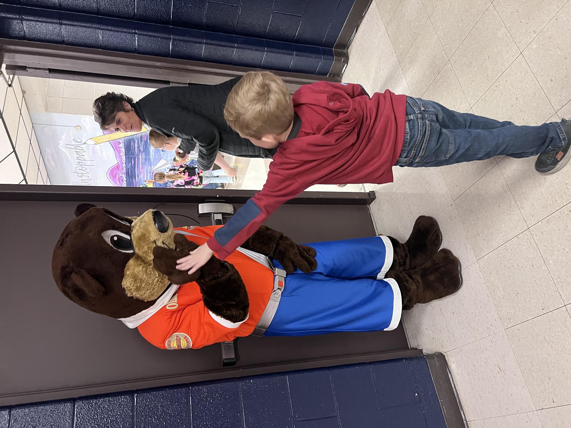 Ollie the Otter giving a high five to a student