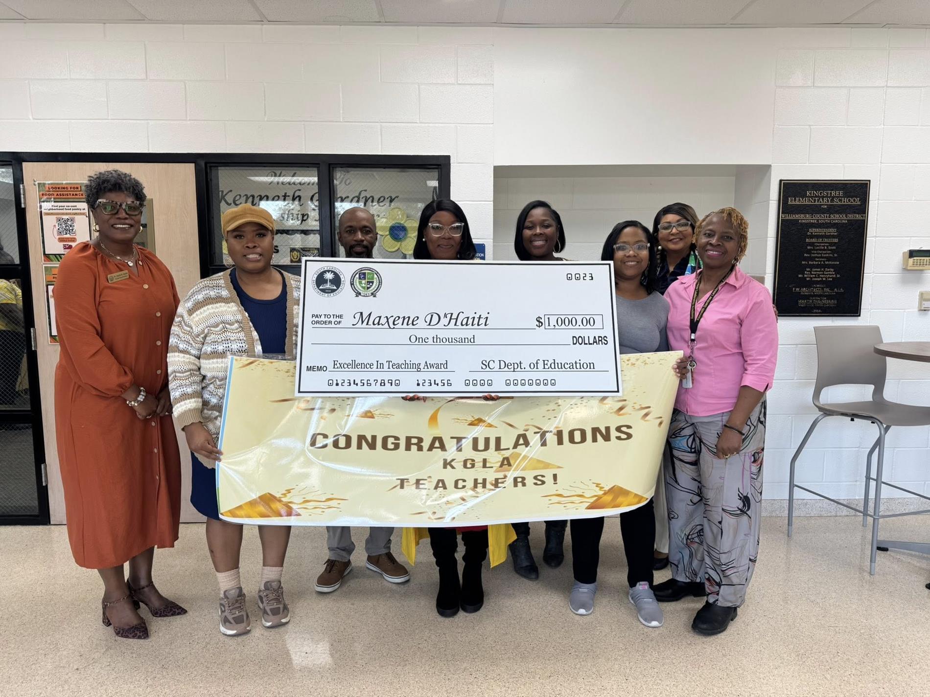 people standing in hallway holding large check 