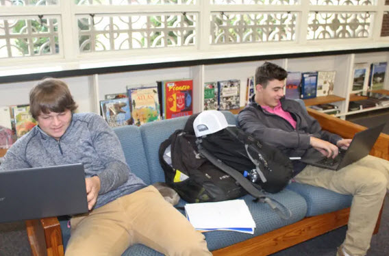 youth on laptops in library