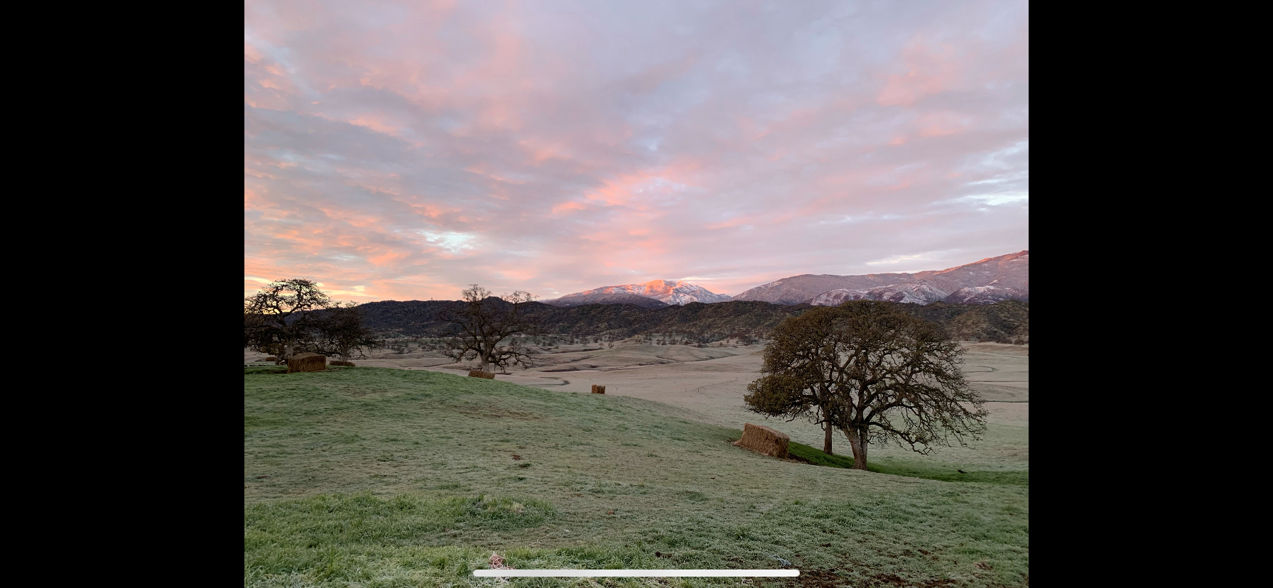 Photo By: Tristen Groteguth March 17, 2022 - Sunrise over a frost covered hilly field with snow-capped mountains in background