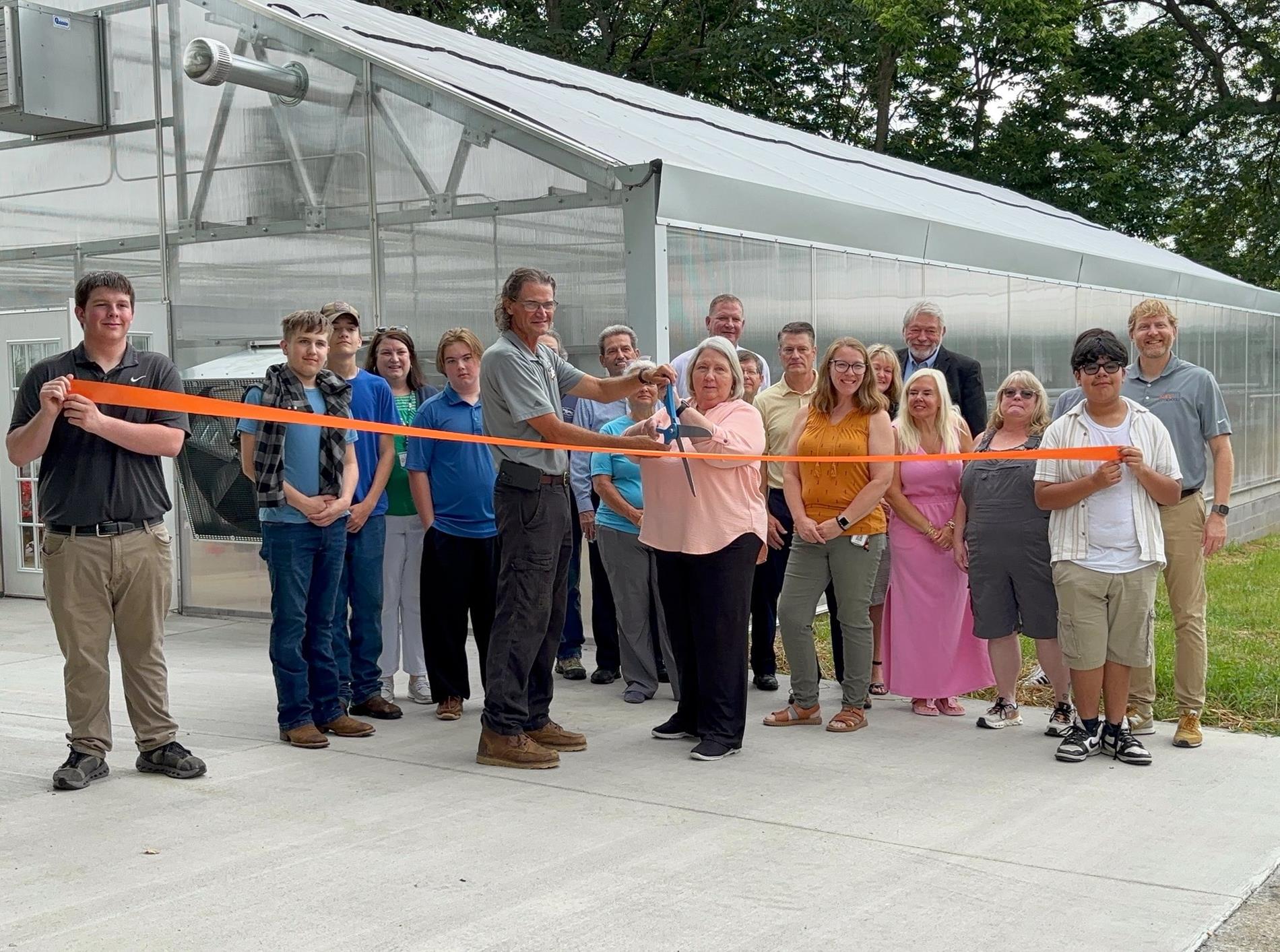 People cutting ribbon in front of Greenhouse