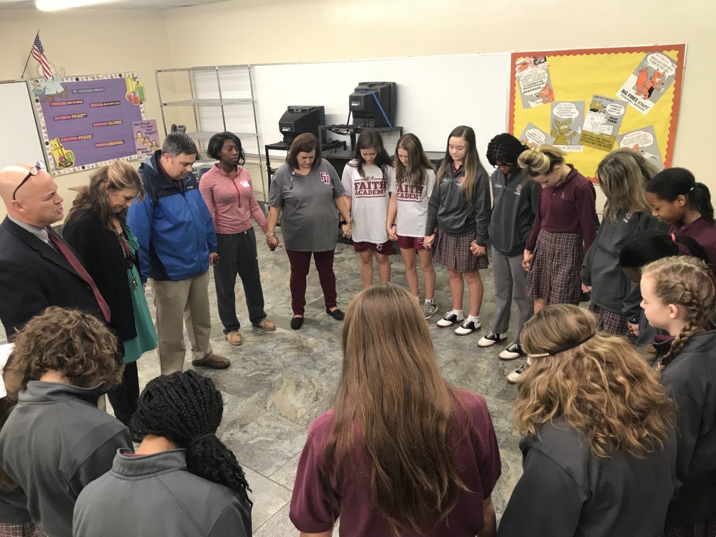 teachers and students in circle praying