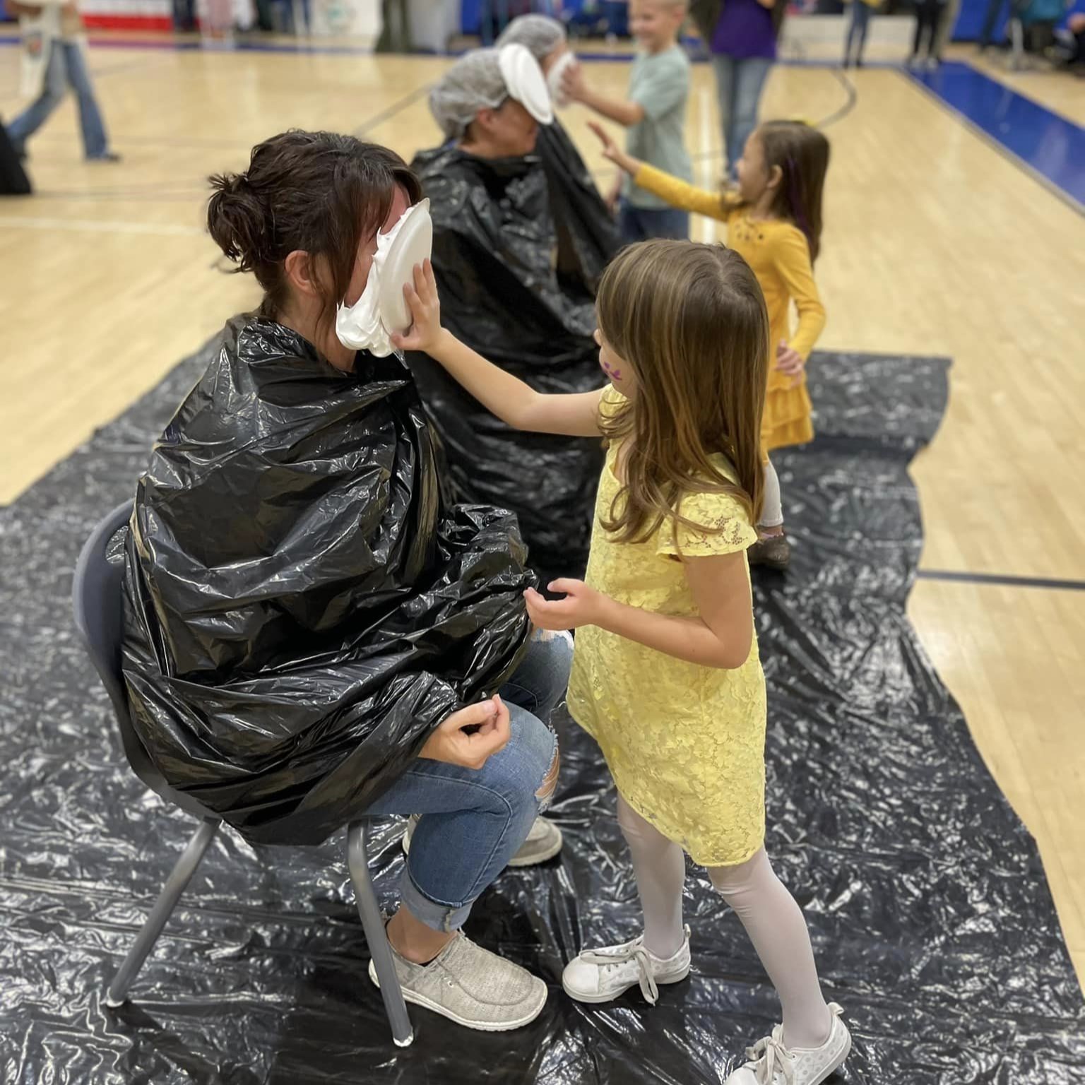 Students putting pie in face of staff