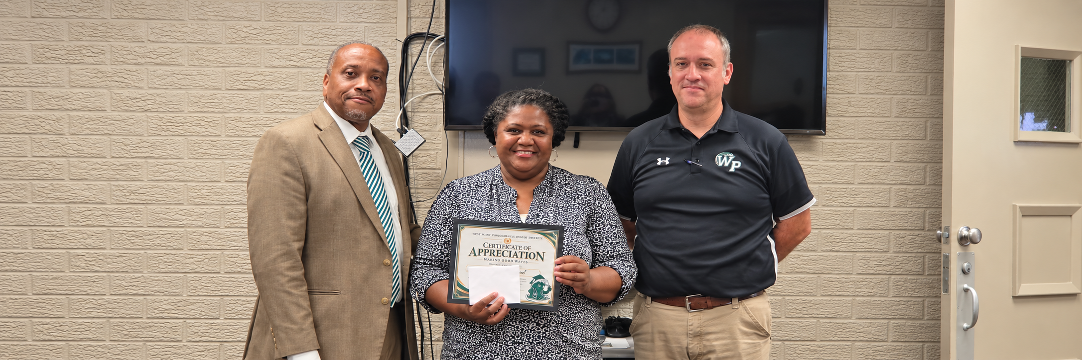 WPCSD Superintendent Dr. Jermaine Taylor and CTC Principal Patrick Ray standing with Career & Technology Center Counselor Tracey Hammond as she holds her Making Good Waves certificate of appreciation at a Board of Education meeting.