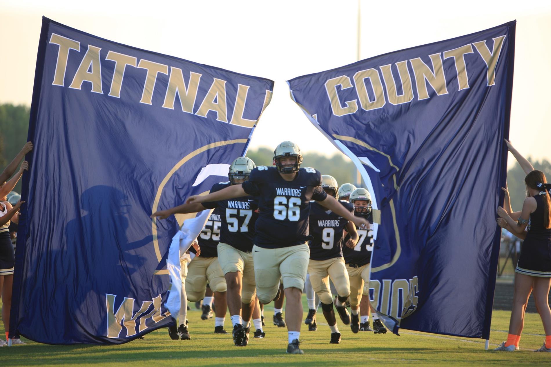 Football players coming through banner