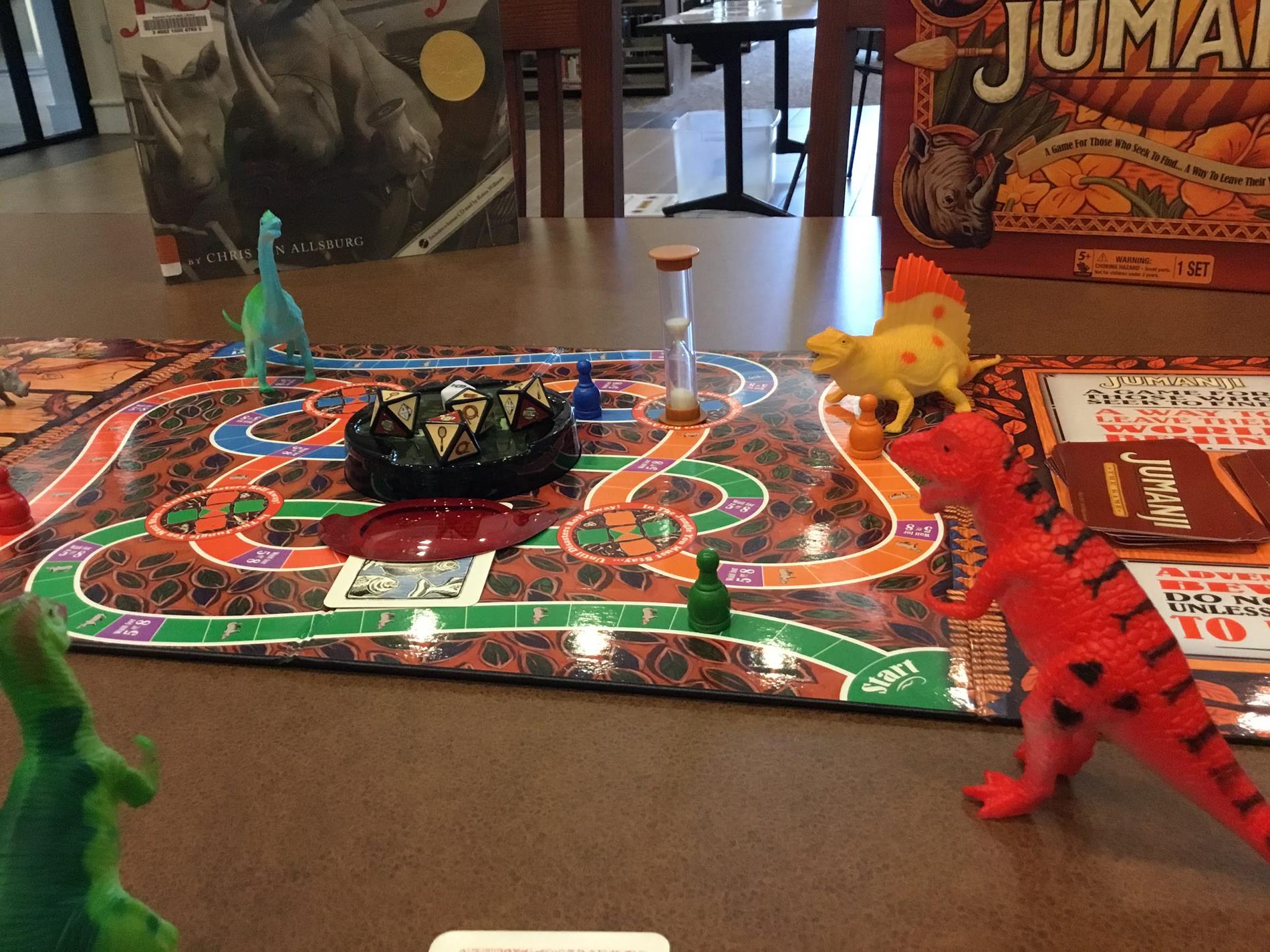 toy dinosaur figures arranged on the game board of the Jumanji board game.