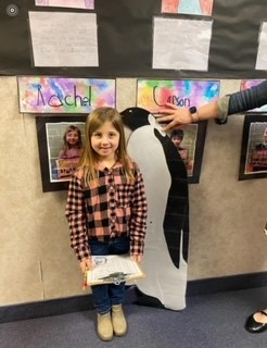 Child being measured to the height of a penguin