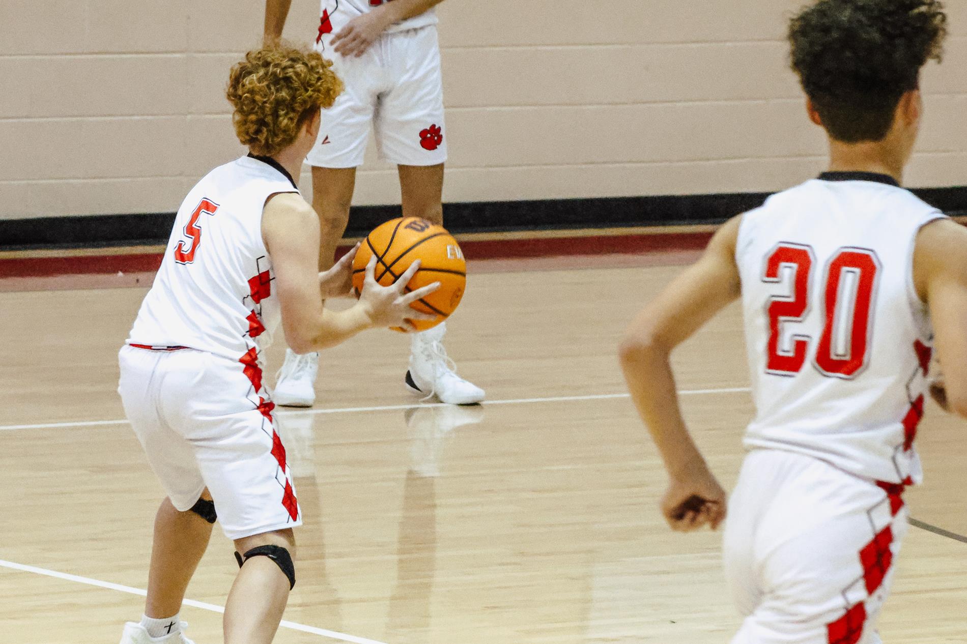 Boys basketball player dribbling ball past midcourt