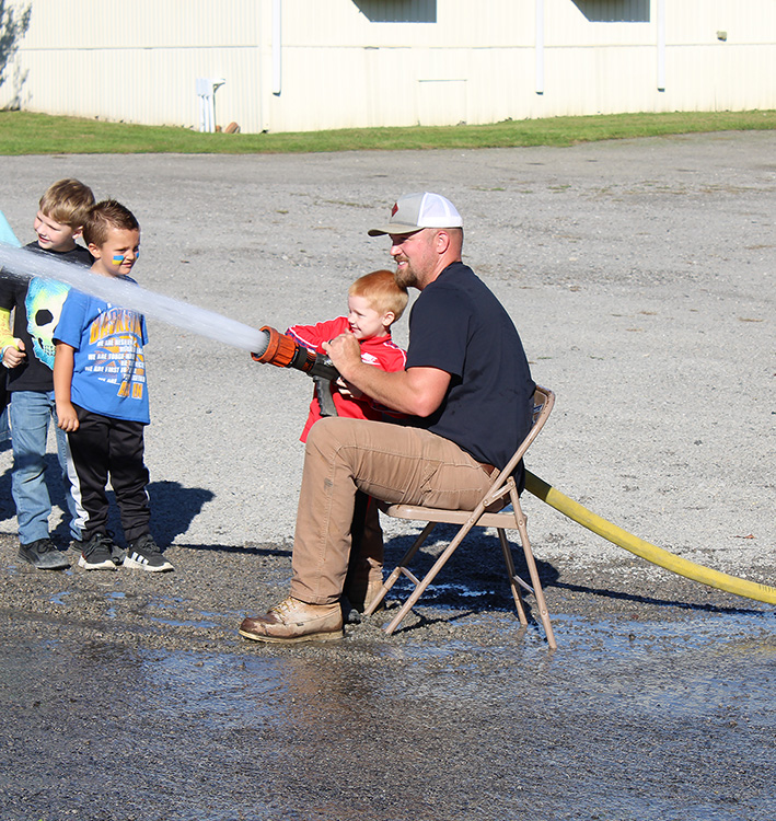 Fire Fighter Andrew Russell helps students with the fire hose