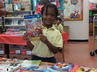young student holding up a book