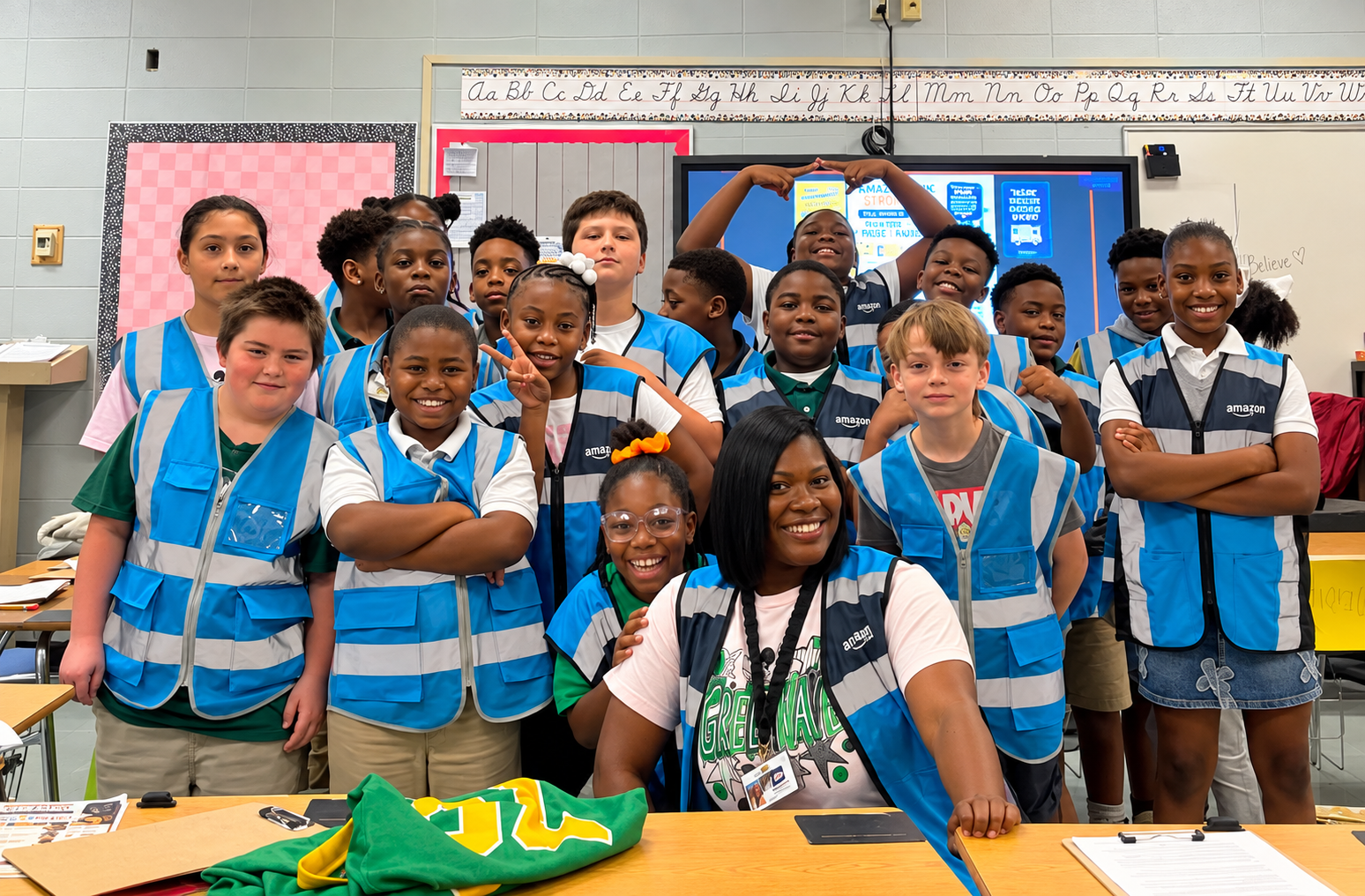 Ms. Morris and her 4th grade students pose together wearing Amazon-style delivery vests after completing a Labor Day ELA activity focused on teamwork, responsibility, and problem-solving.