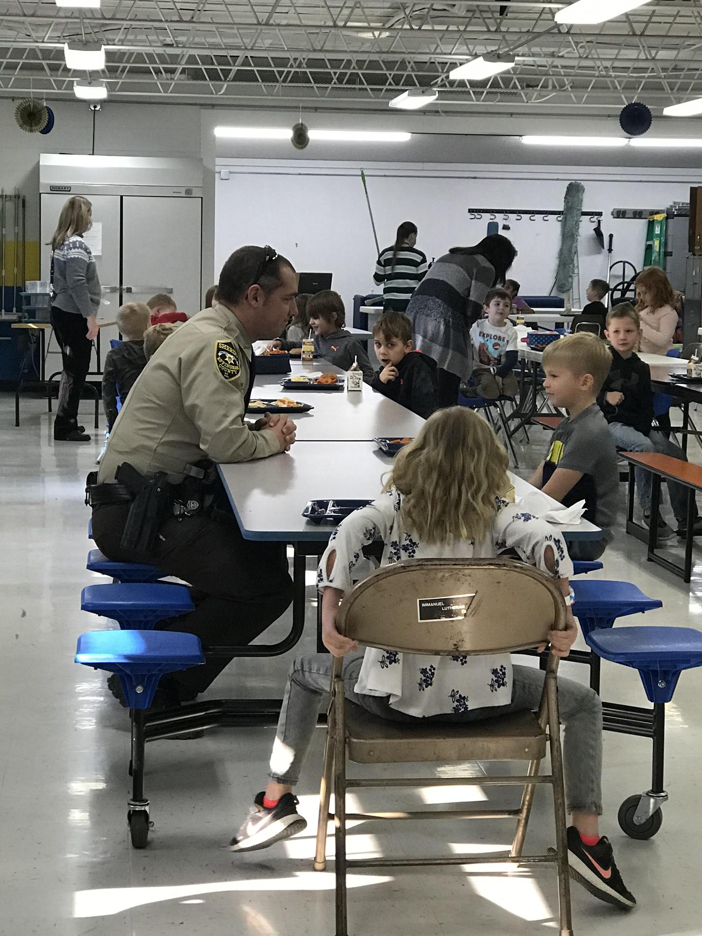 Lower grade students having lunch and talking with Officer Ritz.