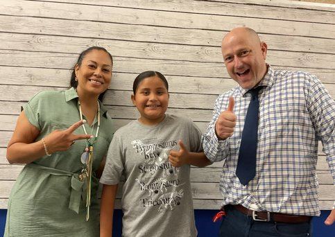 A fifth grade student with two staff members giving a thumbs up