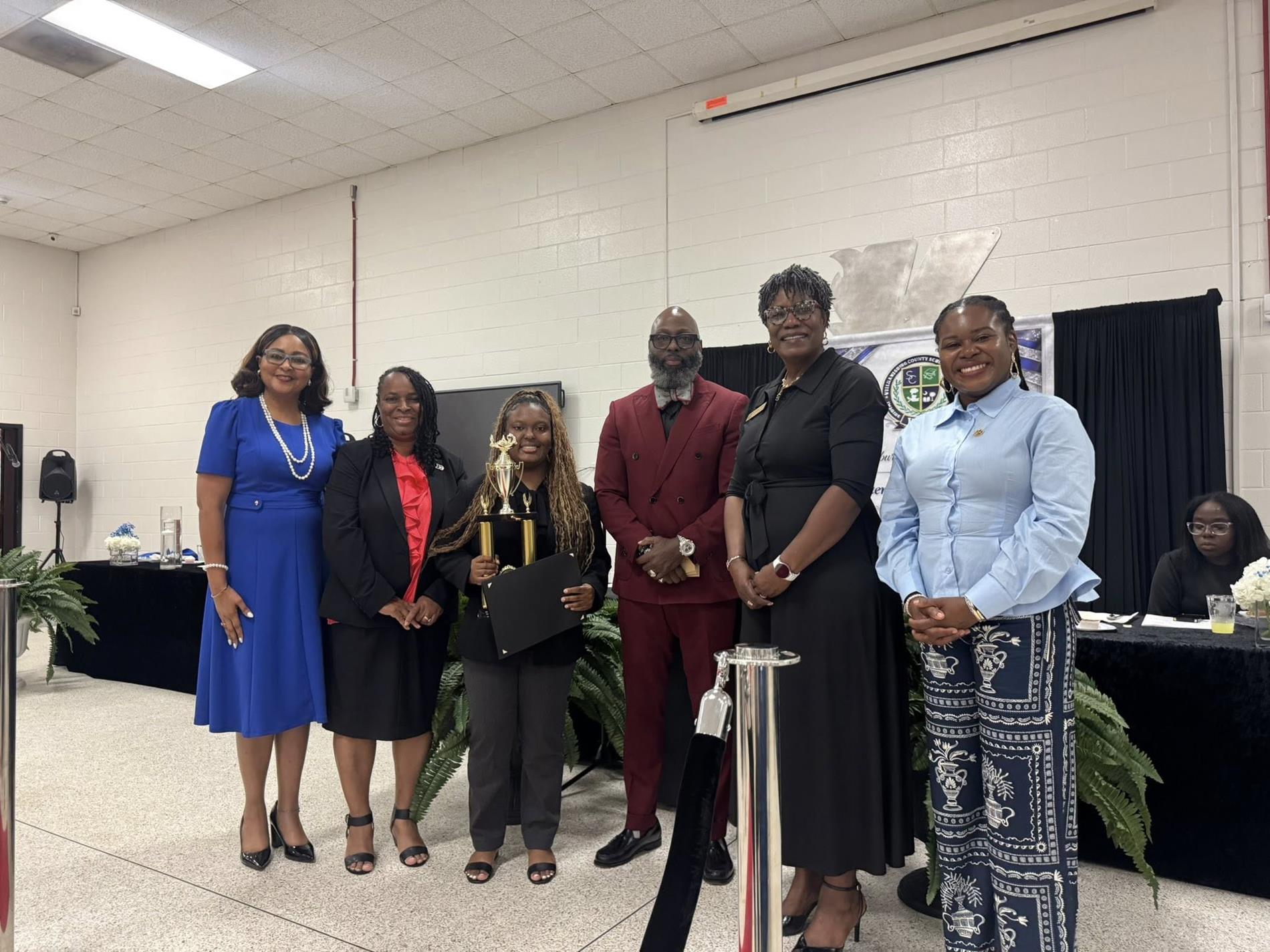 people standing together. one is receiving an award 