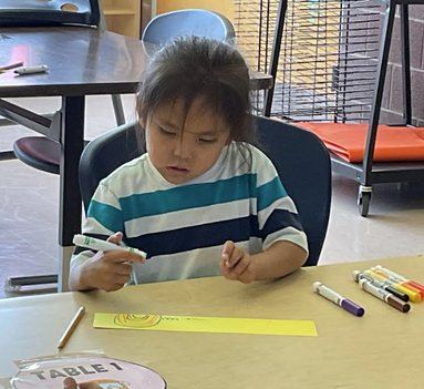 A first grade student practicing writing at his desk