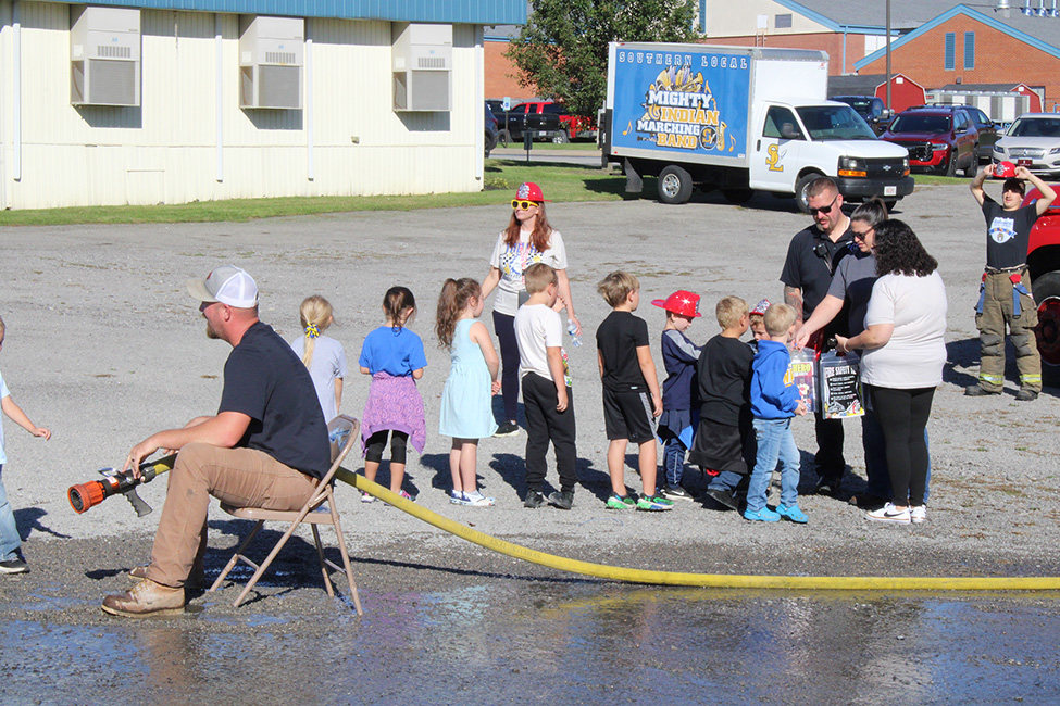 Fire Fighter Andrew Russell helps students with the fire hose