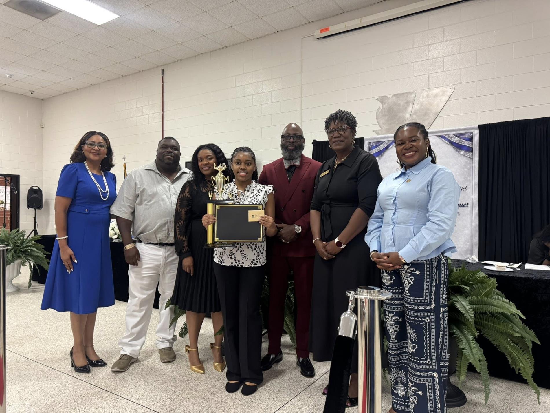 people standing together. one is receiving an award 