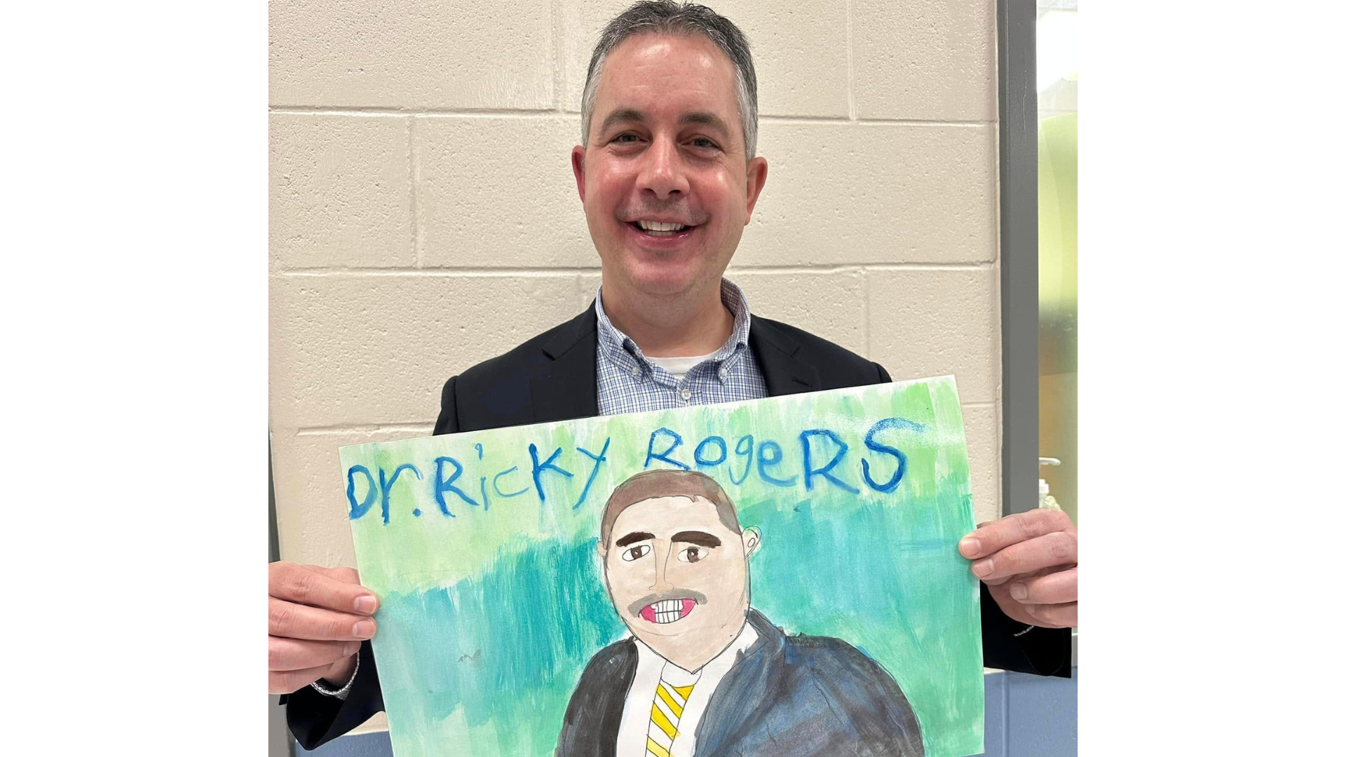 Dr. Rogers holding student artwork