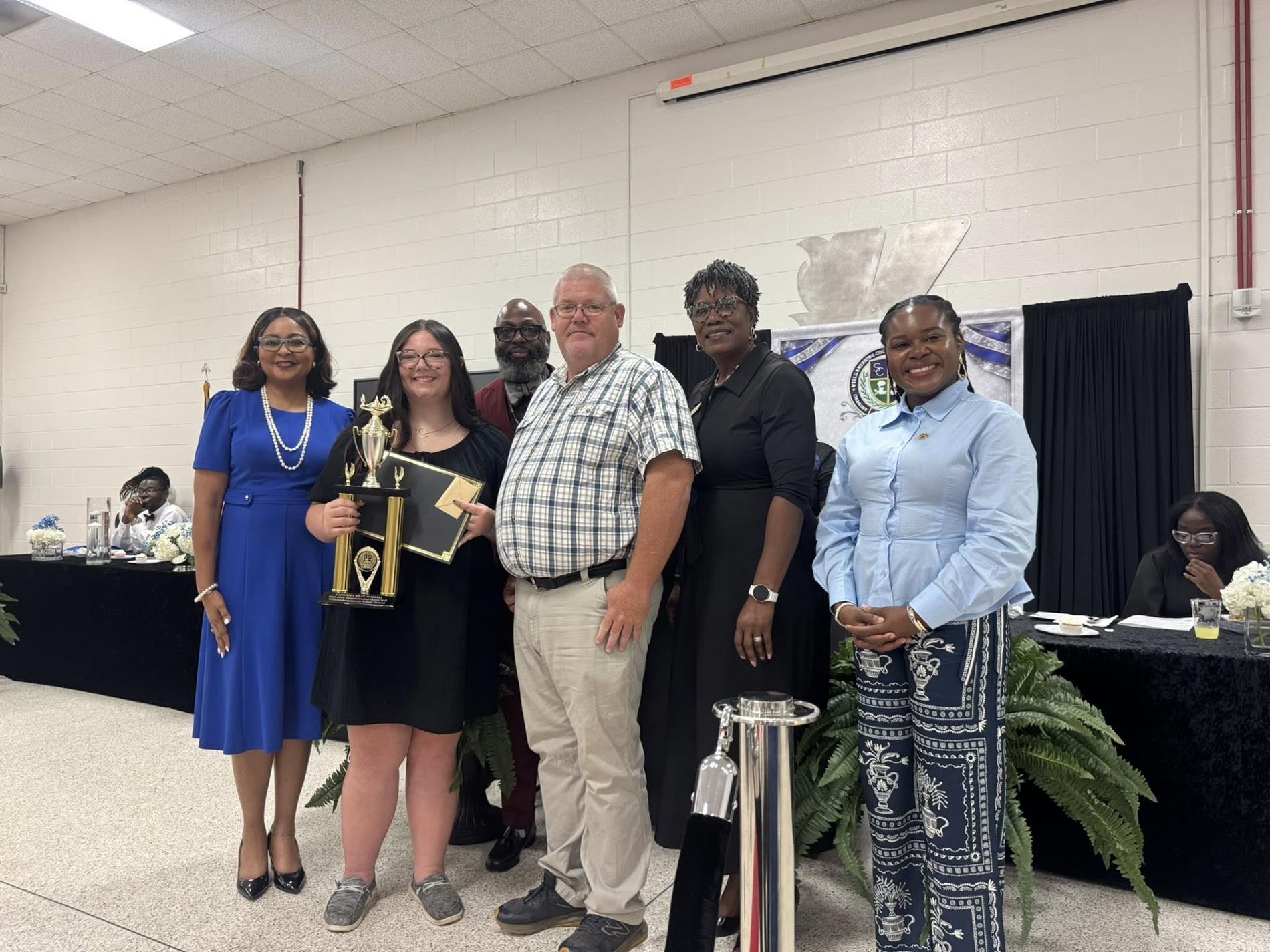 people standing together. one is receiving an award 