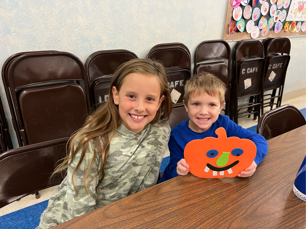 older girl and younger boy with pumpkin craft