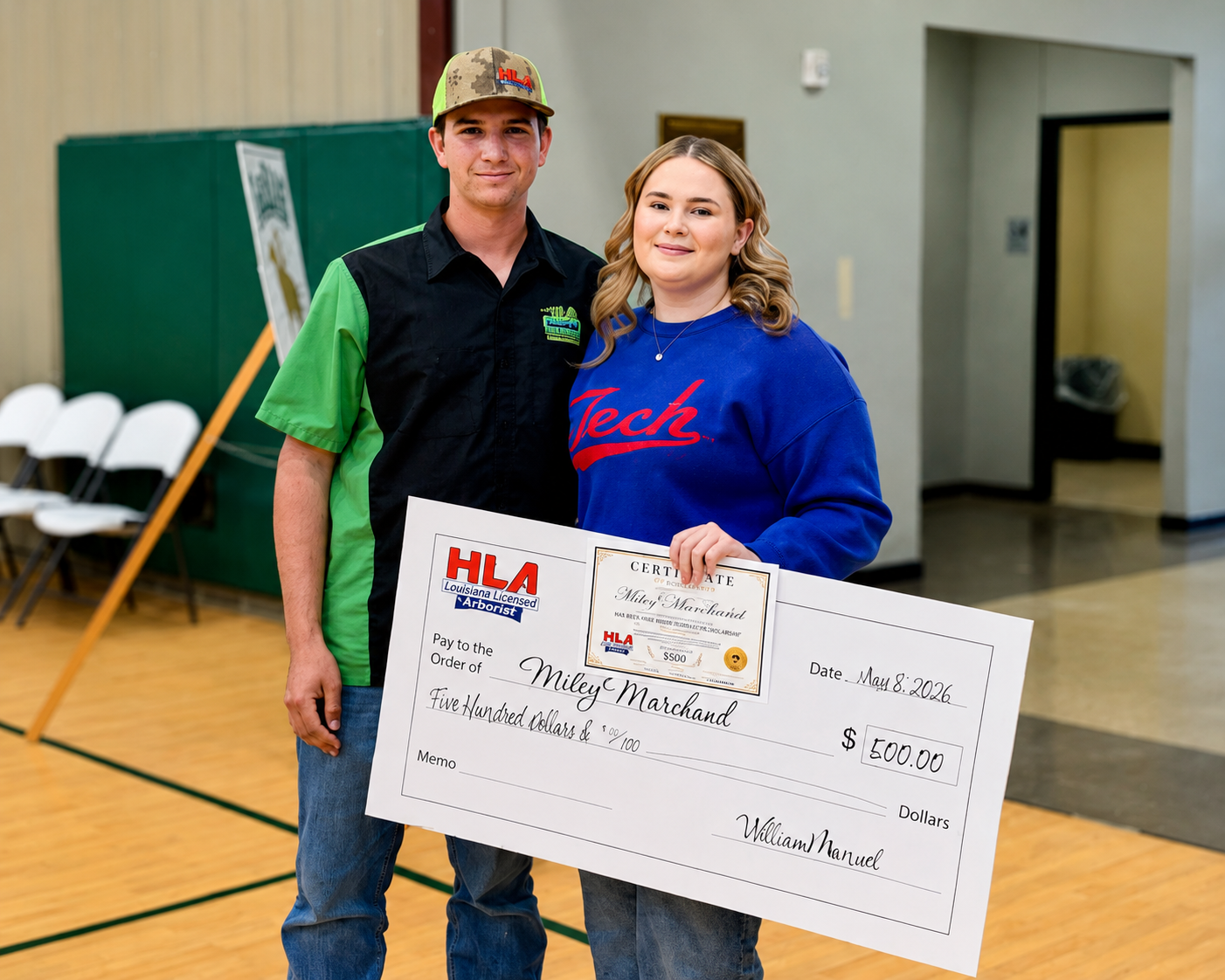 LaSAS alumnus William Manuel of HLA Tree Service presents 2026 LaSAS graduate Miley Marchand with the $500 HLA Tree Service Community Scholarship. The two stand together at LaSAS as Marchand holds the scholarship certificate and presentation check.