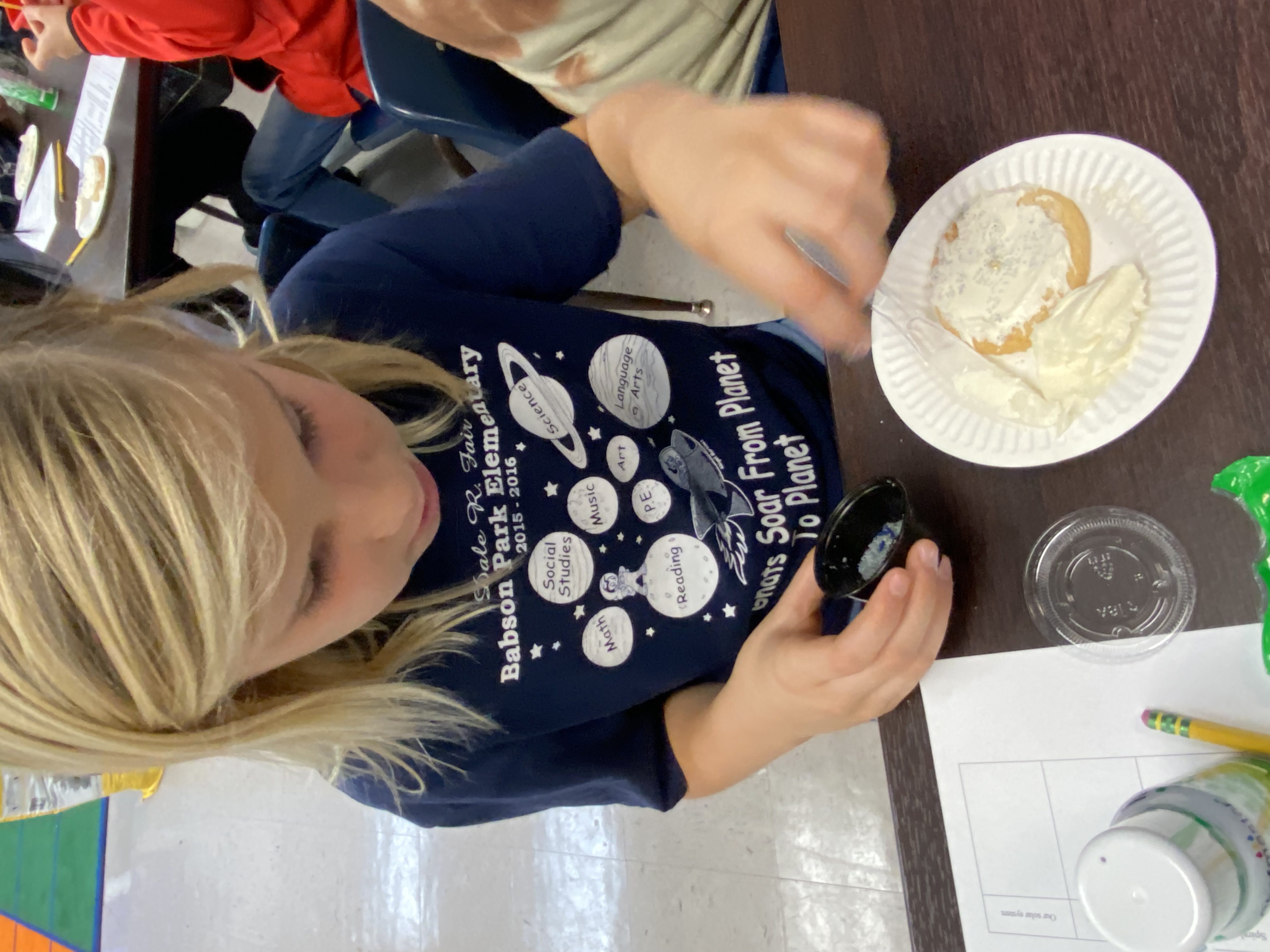 A 5th grade student creating the spiral arms of their galaxy cookie.