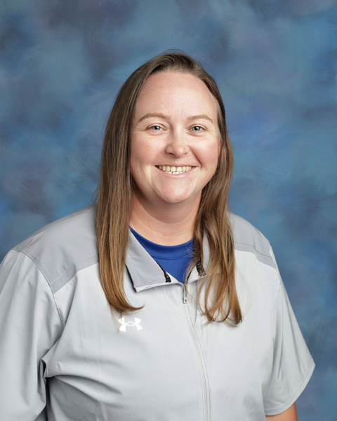 Teacher smiling against a blue background