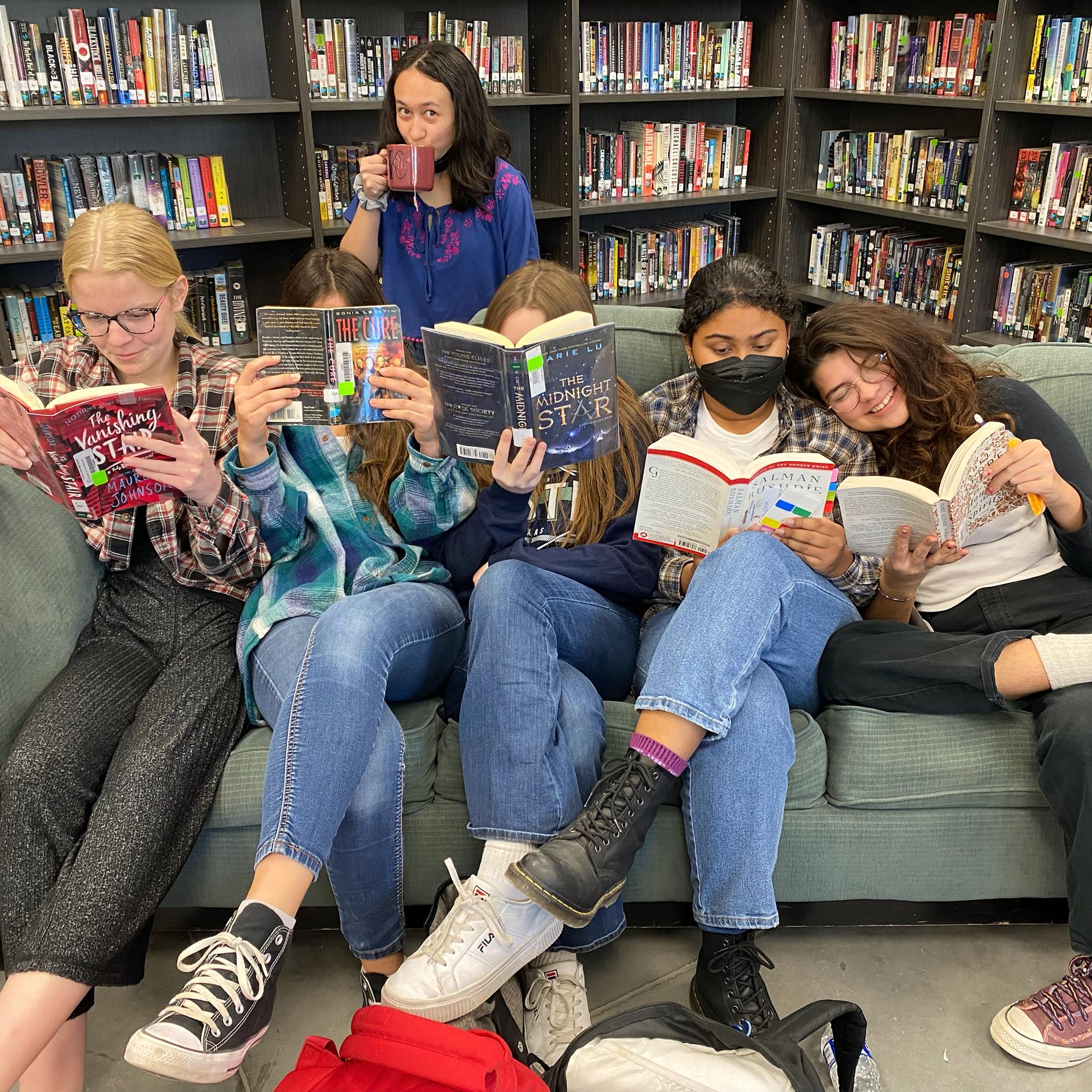 Lit Club getting cozy with books on the library sofa