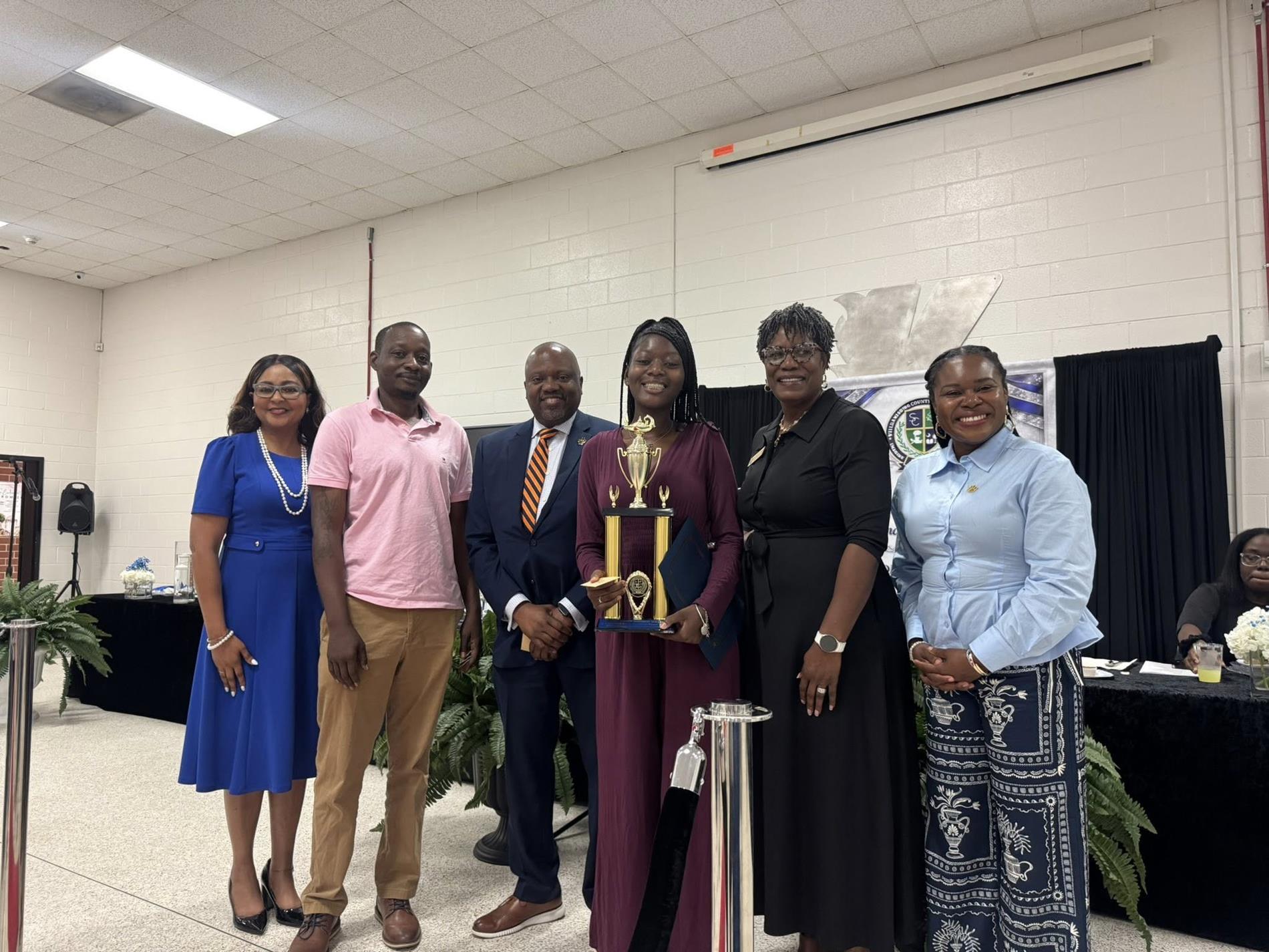 people standing together. one is receiving an award 