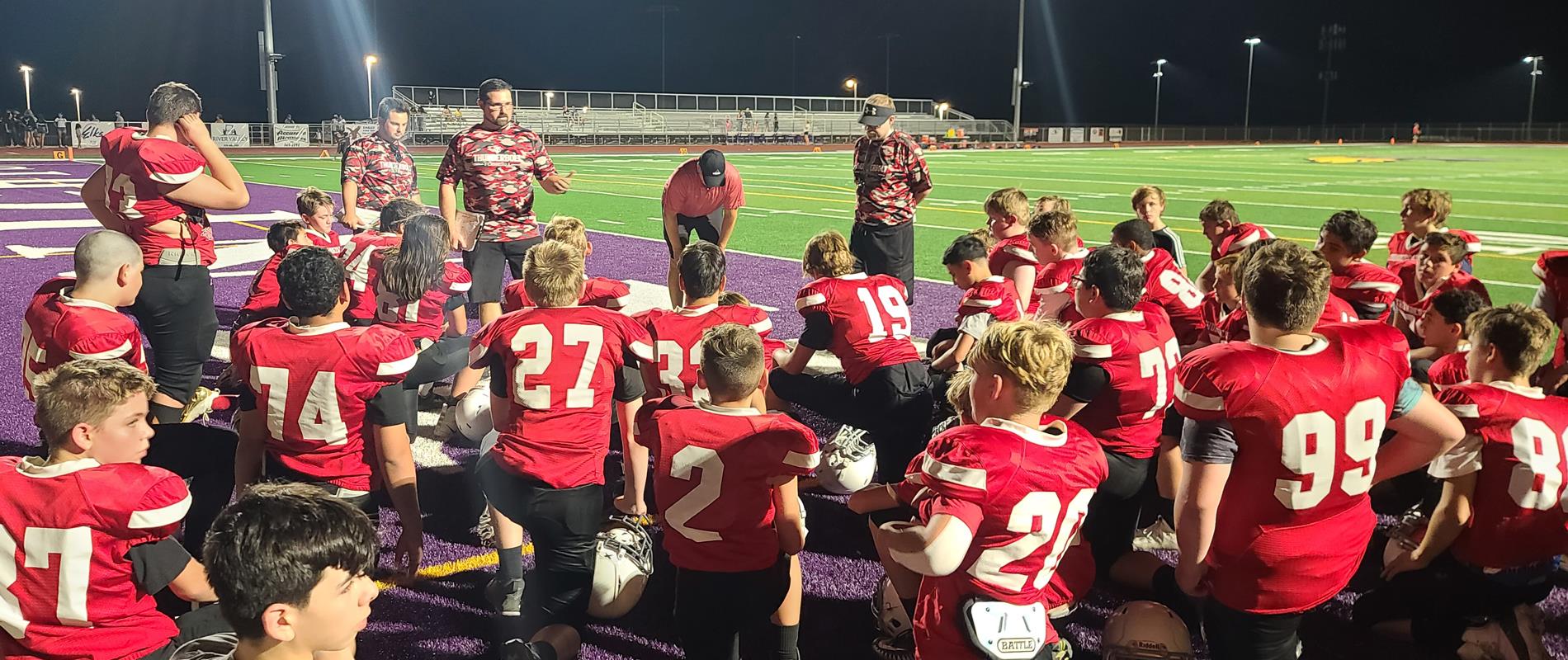 Football team kneels with coaches
