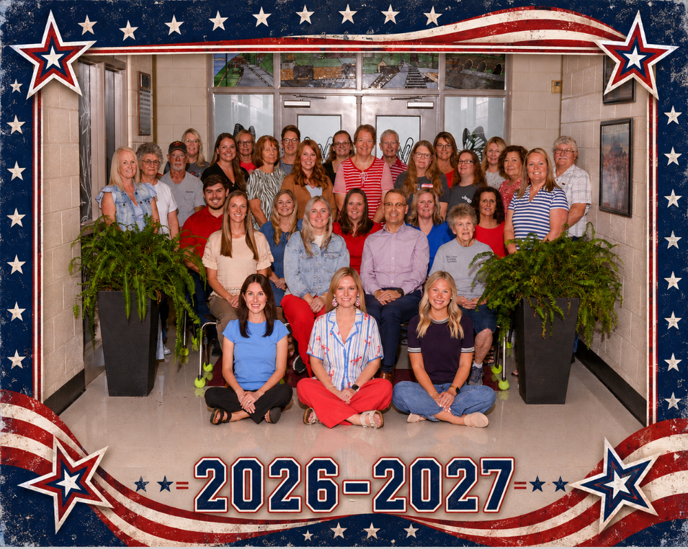 Group picture of WMS teachers wearing red, white and blue for a faculty picture in front of stained glass windows.