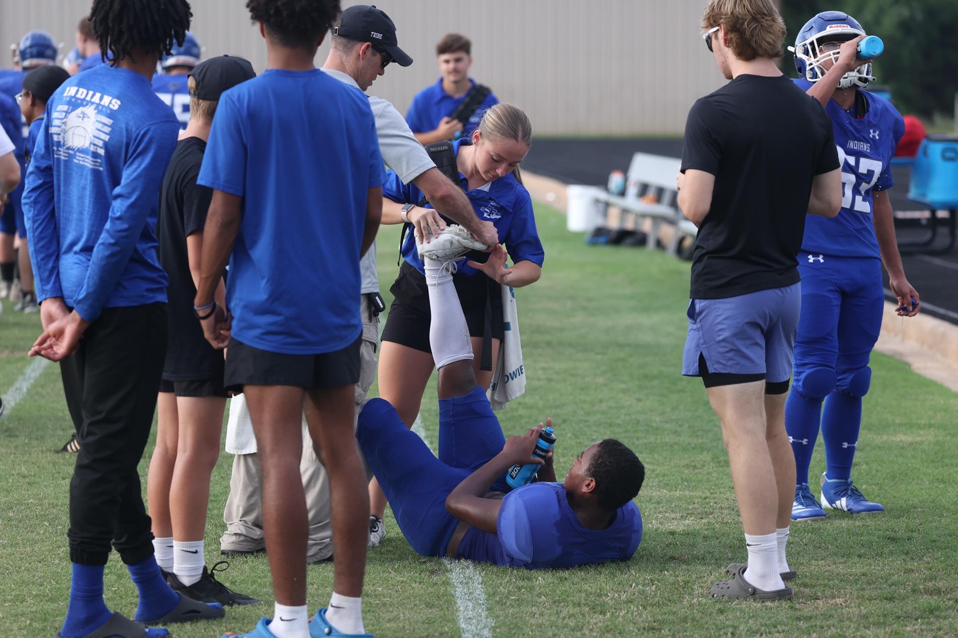 Athletic Trainer and students evaluate injured football player