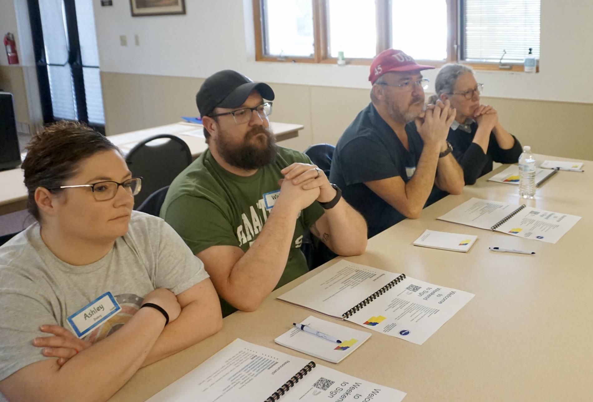 two couples sitting at a table learning sign language