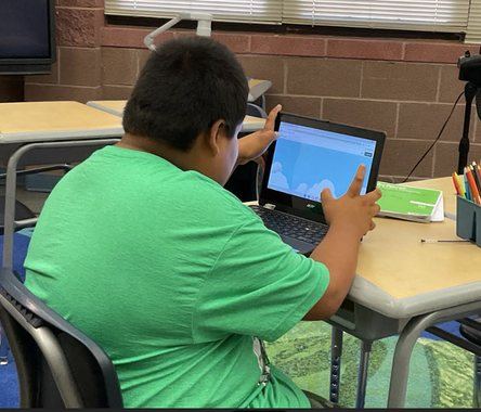 A third grade student working on a tablet at his desk