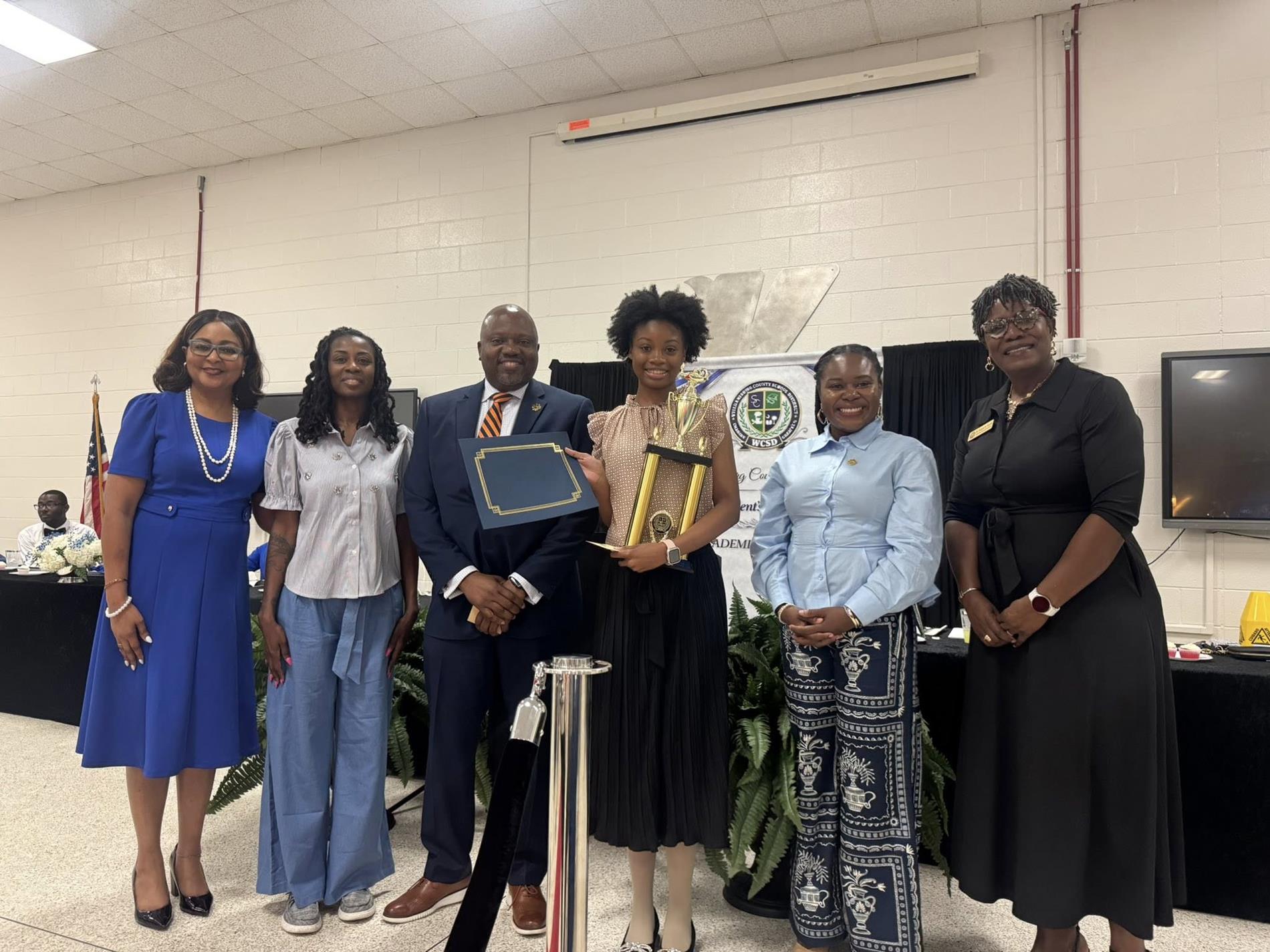 people standing together. one is receiving an award 