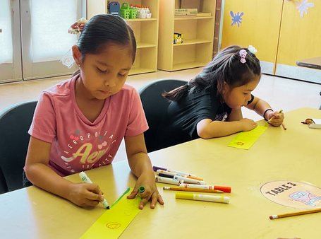 Two Kindergarten students coloring together at a classroom table