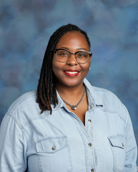 Teacher smiling against a blue background