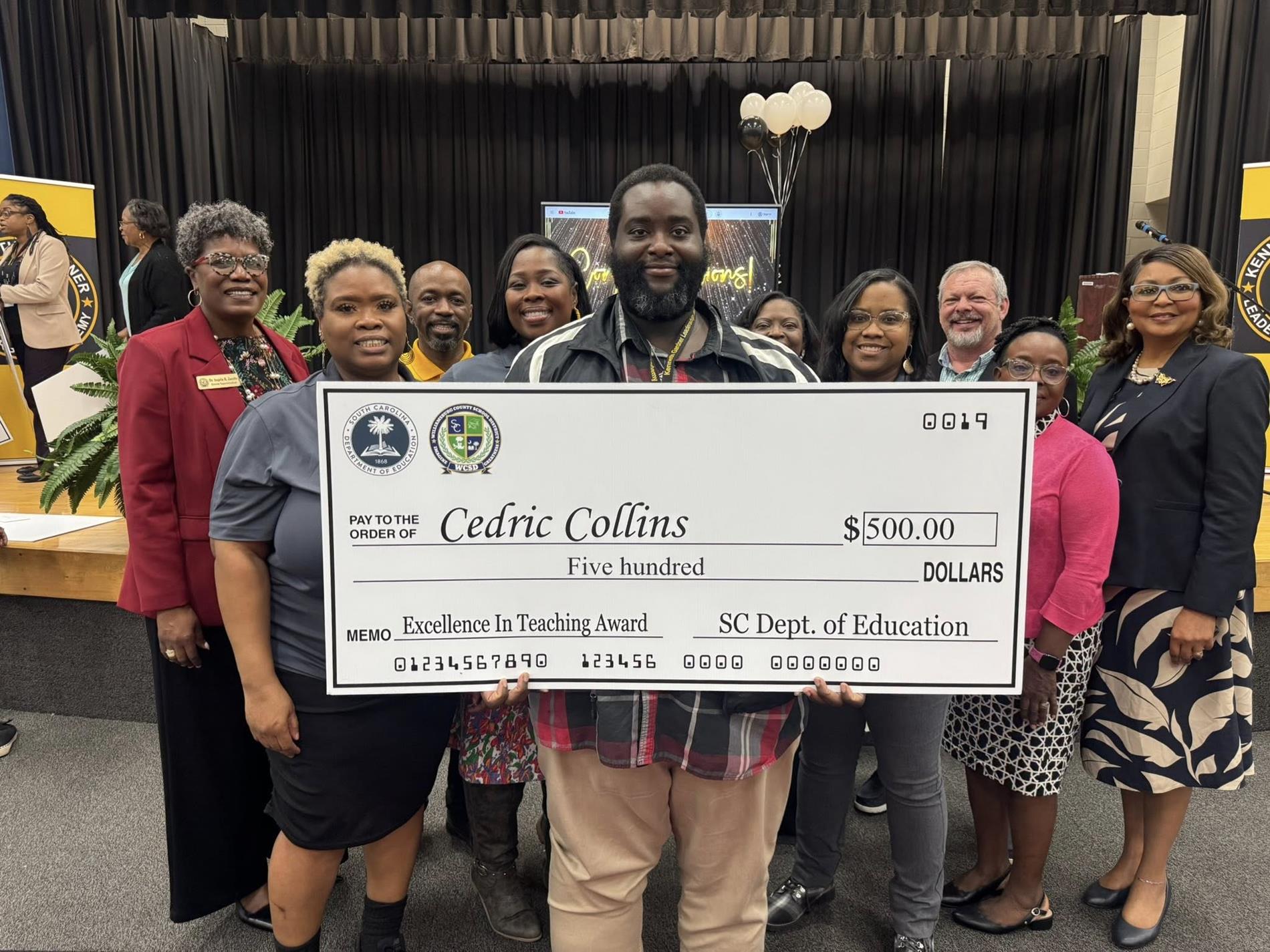 people standing holding large check 