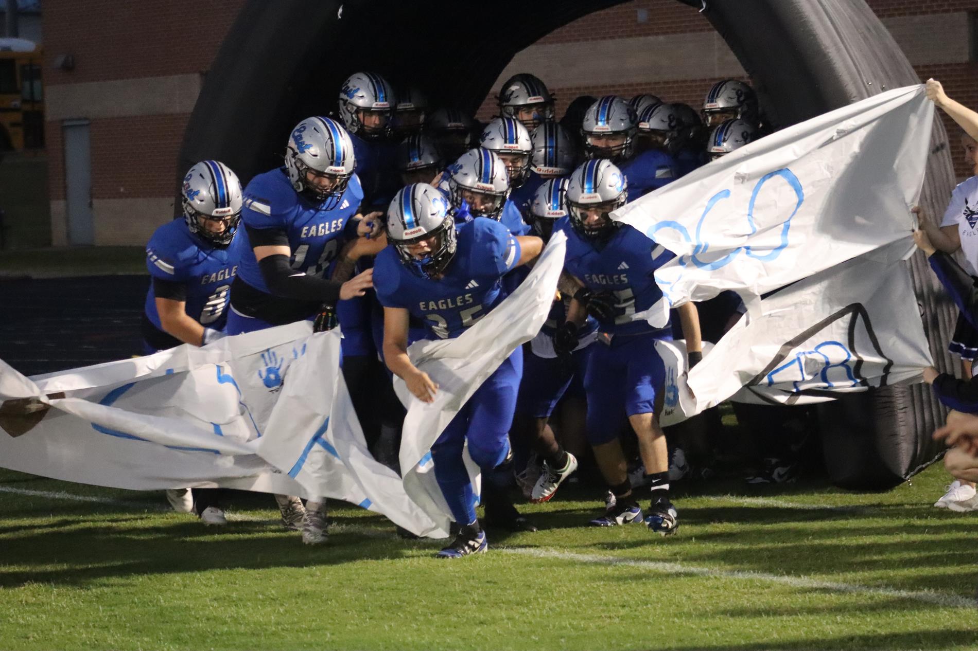 football players ripping through banner to run onto the field