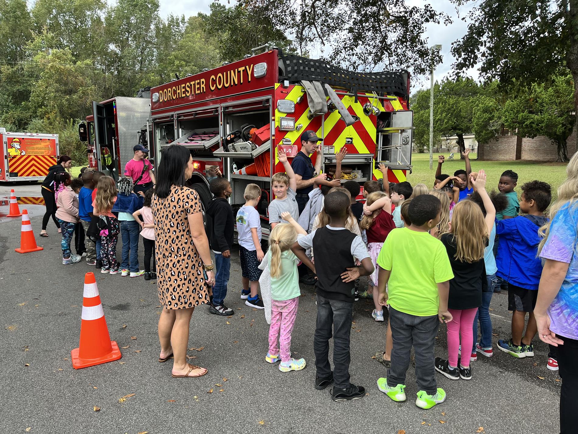 students and teacher looking at fireman and fire truck