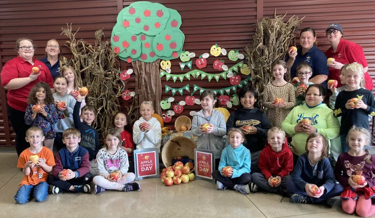 group of young students holding apples