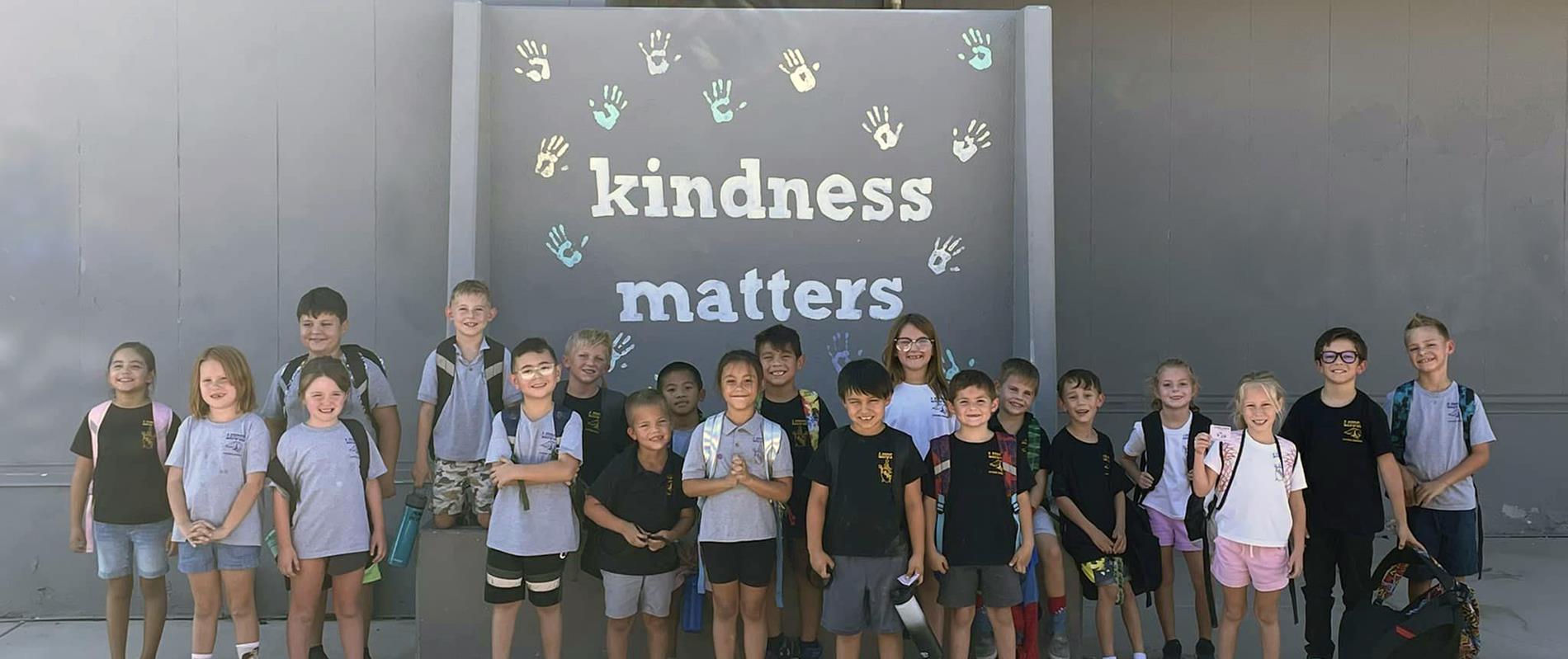 Kindness Club members standing in front of Kindness Matters wall