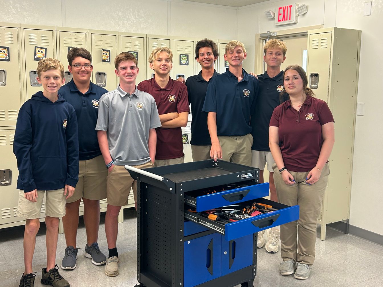 Students posing in classroom near work bench 