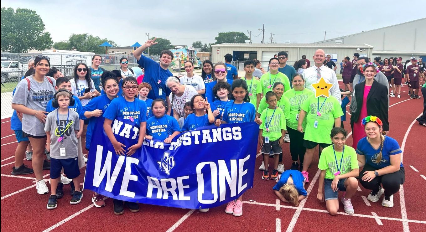 A group of students and teachers holding a mustang relay banner